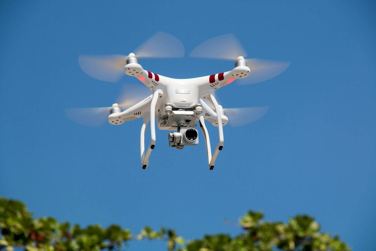 A white drone flying with camera against a clear blue sky in La Libertad.