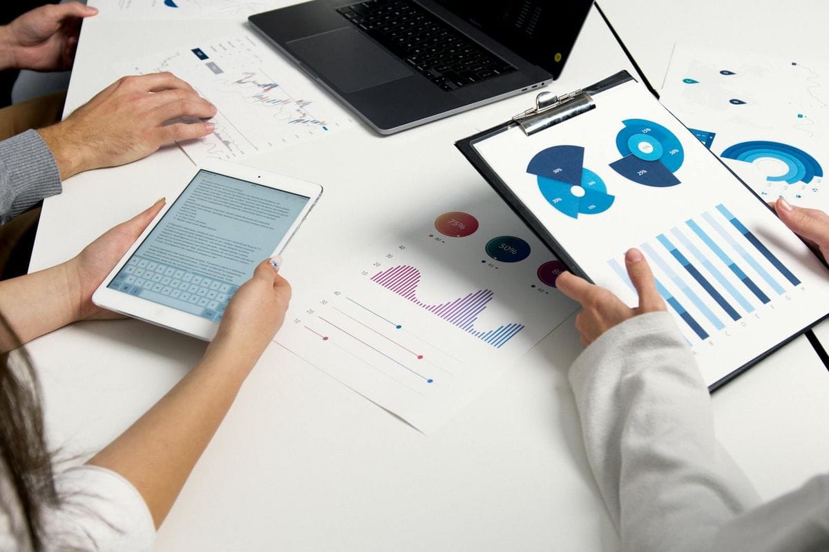 Team analyzing financial charts and digital reports during a business meeting.