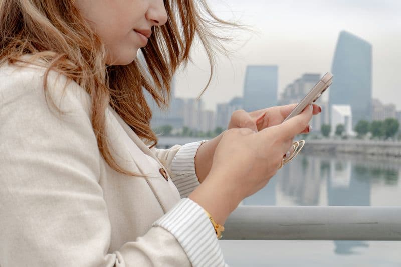 Woman uses her phone in a cityscape.