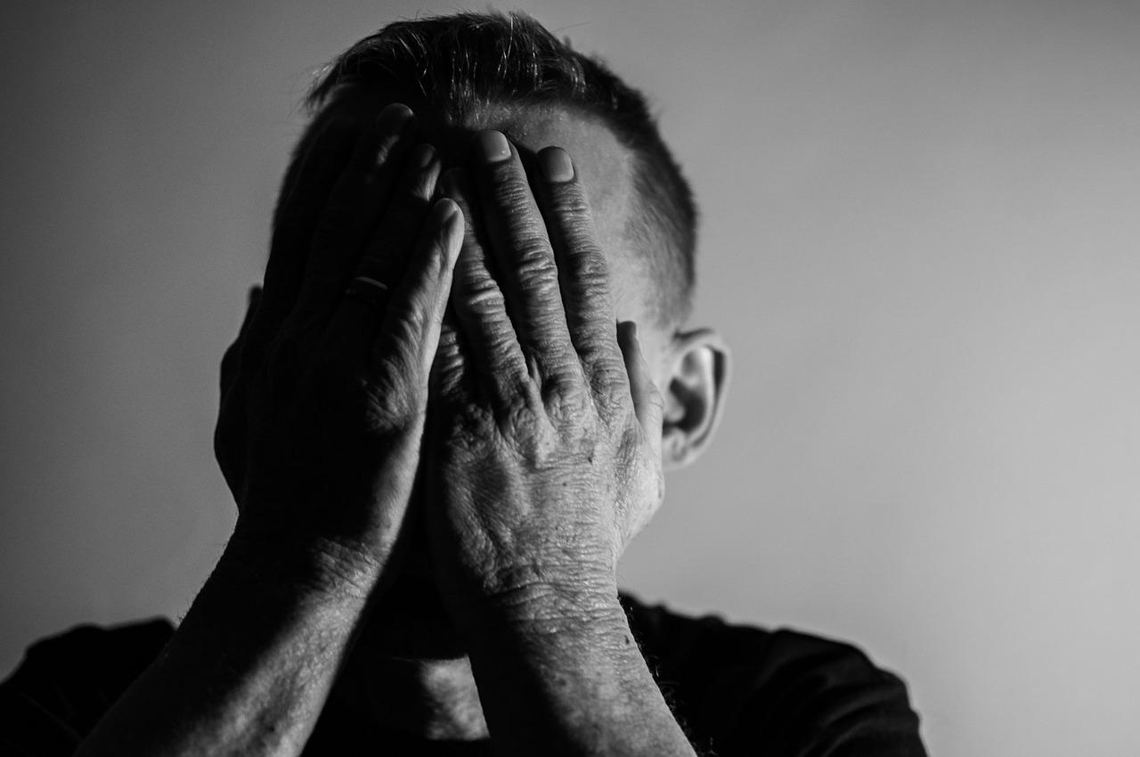 A depressed man with his head in his hands (he probably wishes he could meditate better)