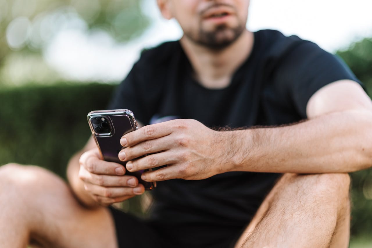A casually dressed man holding a smartphone in both hands, implying natural, hands-on engagement—highlighting authentic human activity on social media