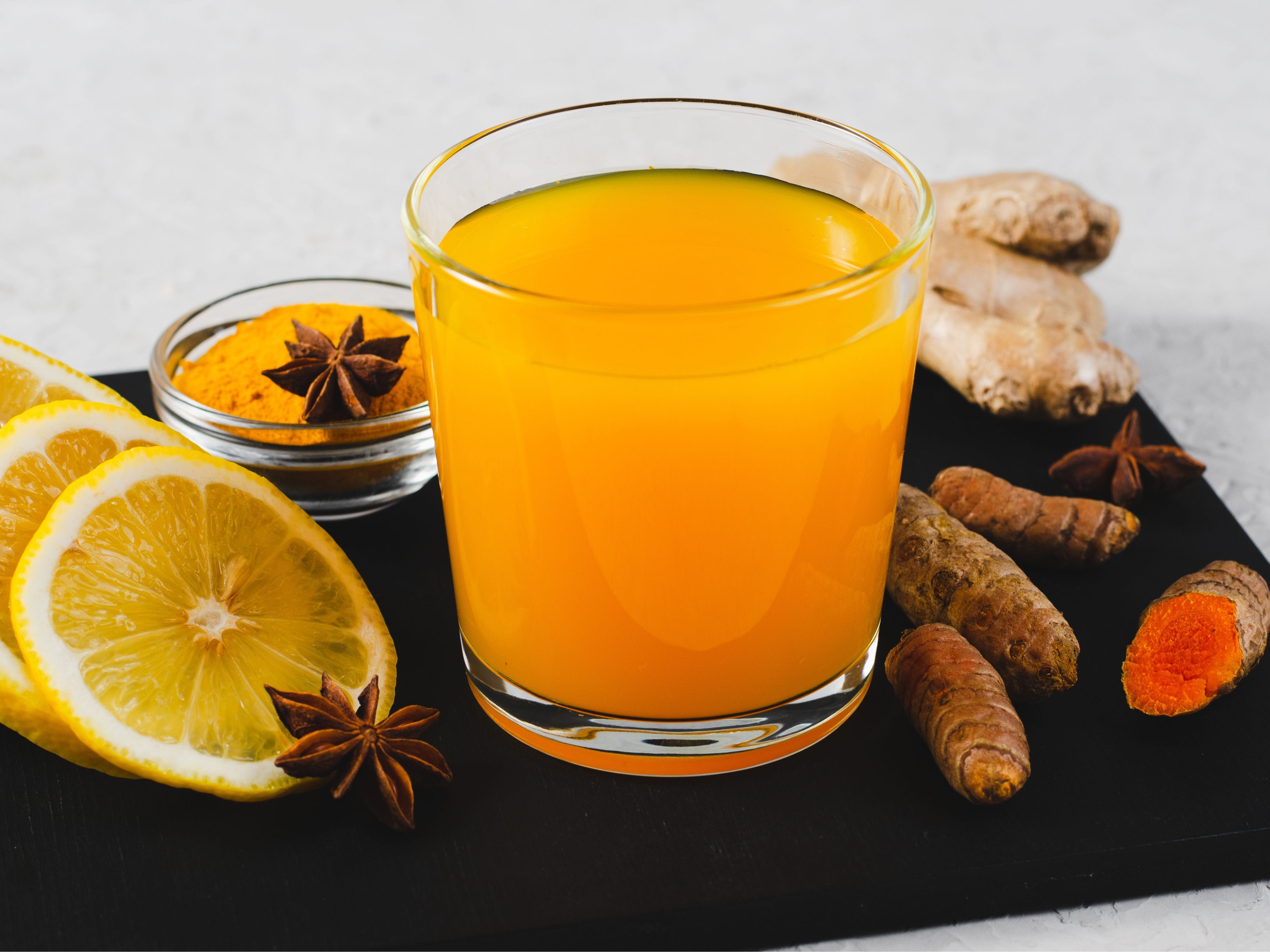 Glass of juice with lemon slices, turmeric, and ginger