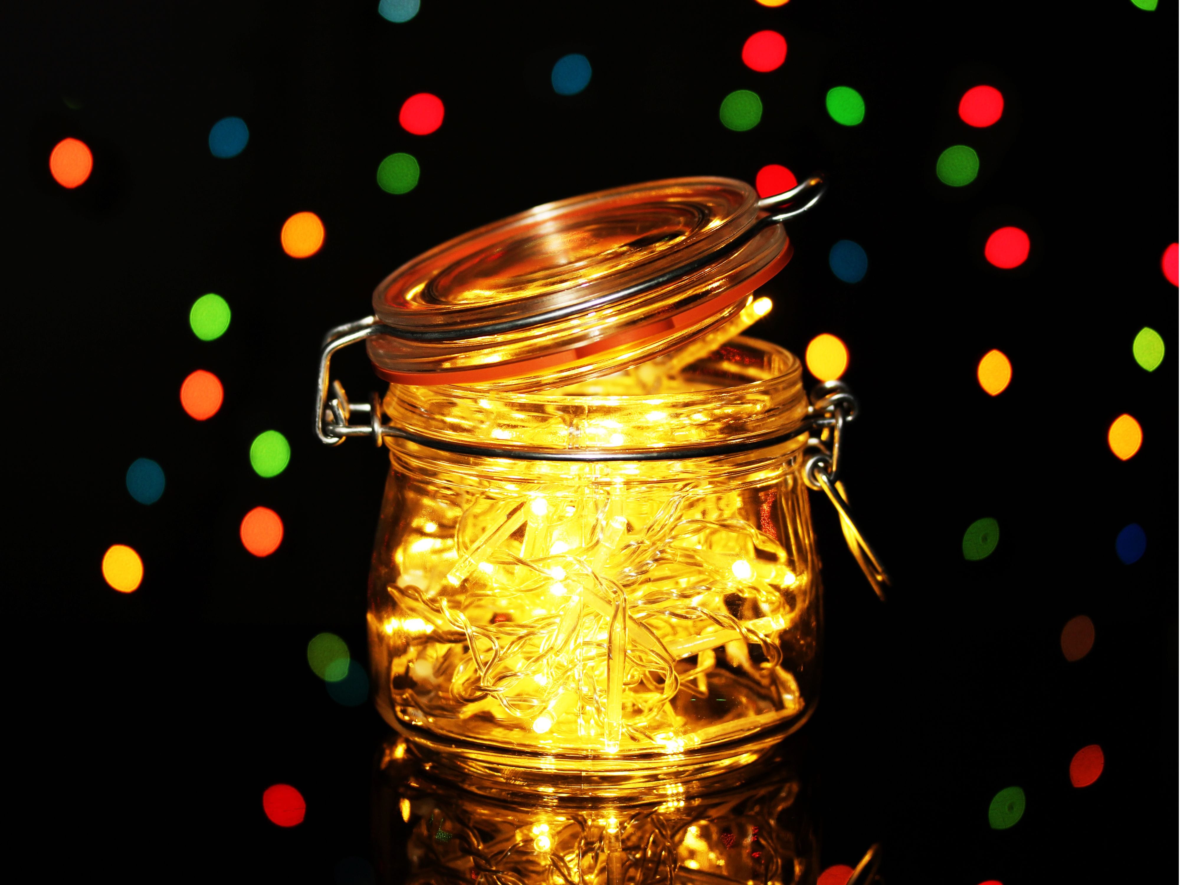 Hand holding a jar filled with lights, turning it into a jar lamp