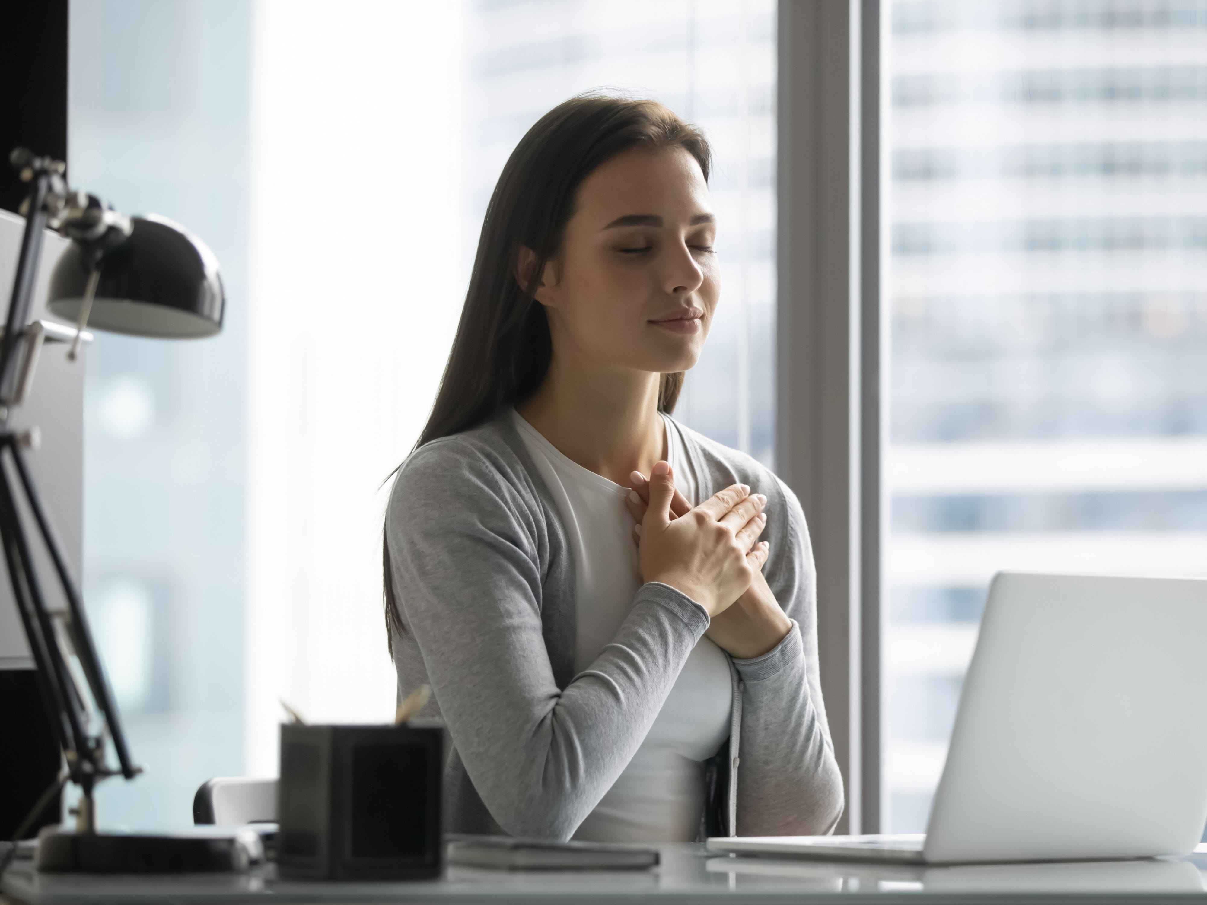 Stressed woman at work holding her heart