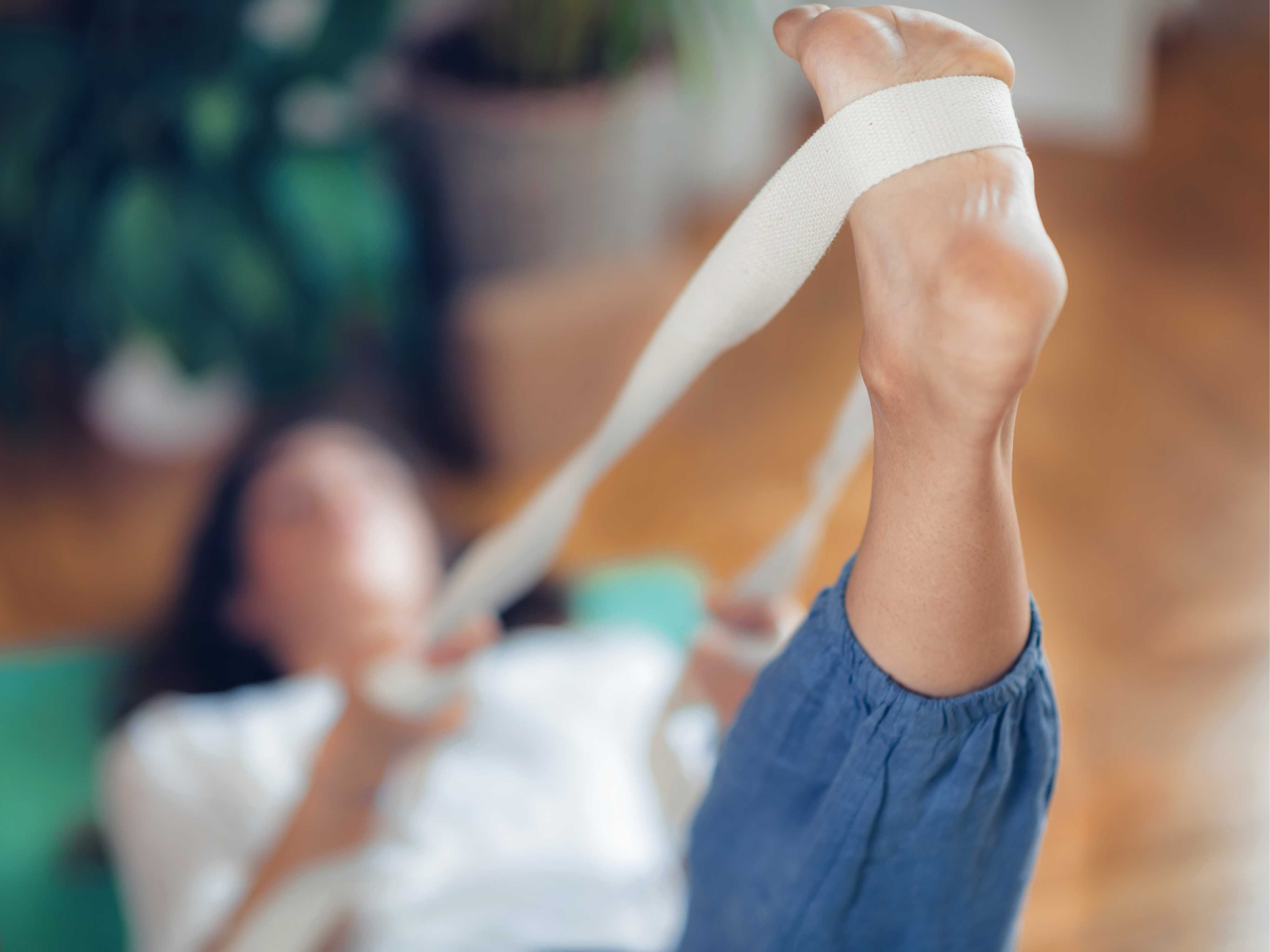 Woman using a yoga strap to stretch her leg upright