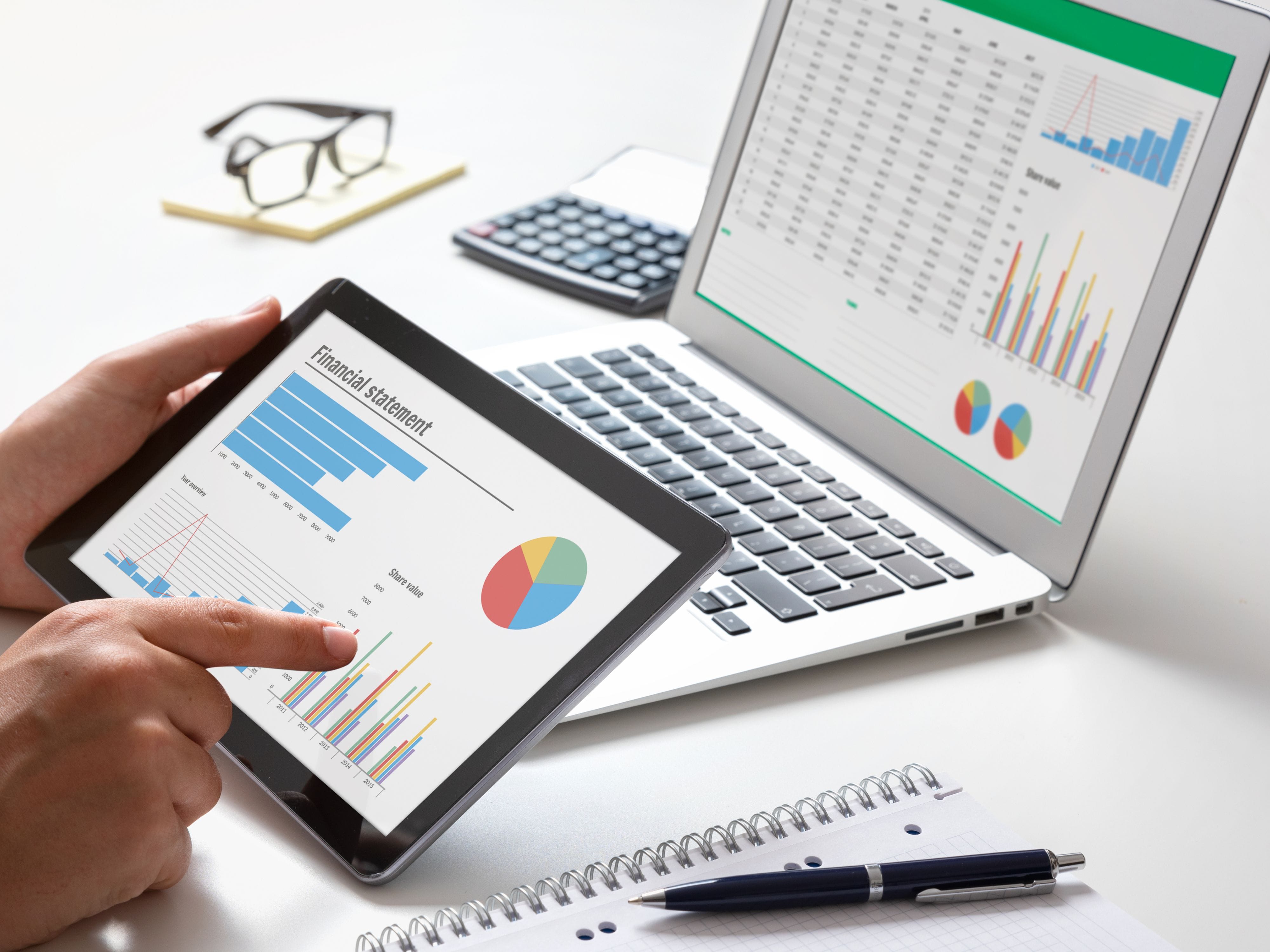 Person analyzing financial stats on laptop and tablet – finance expert online