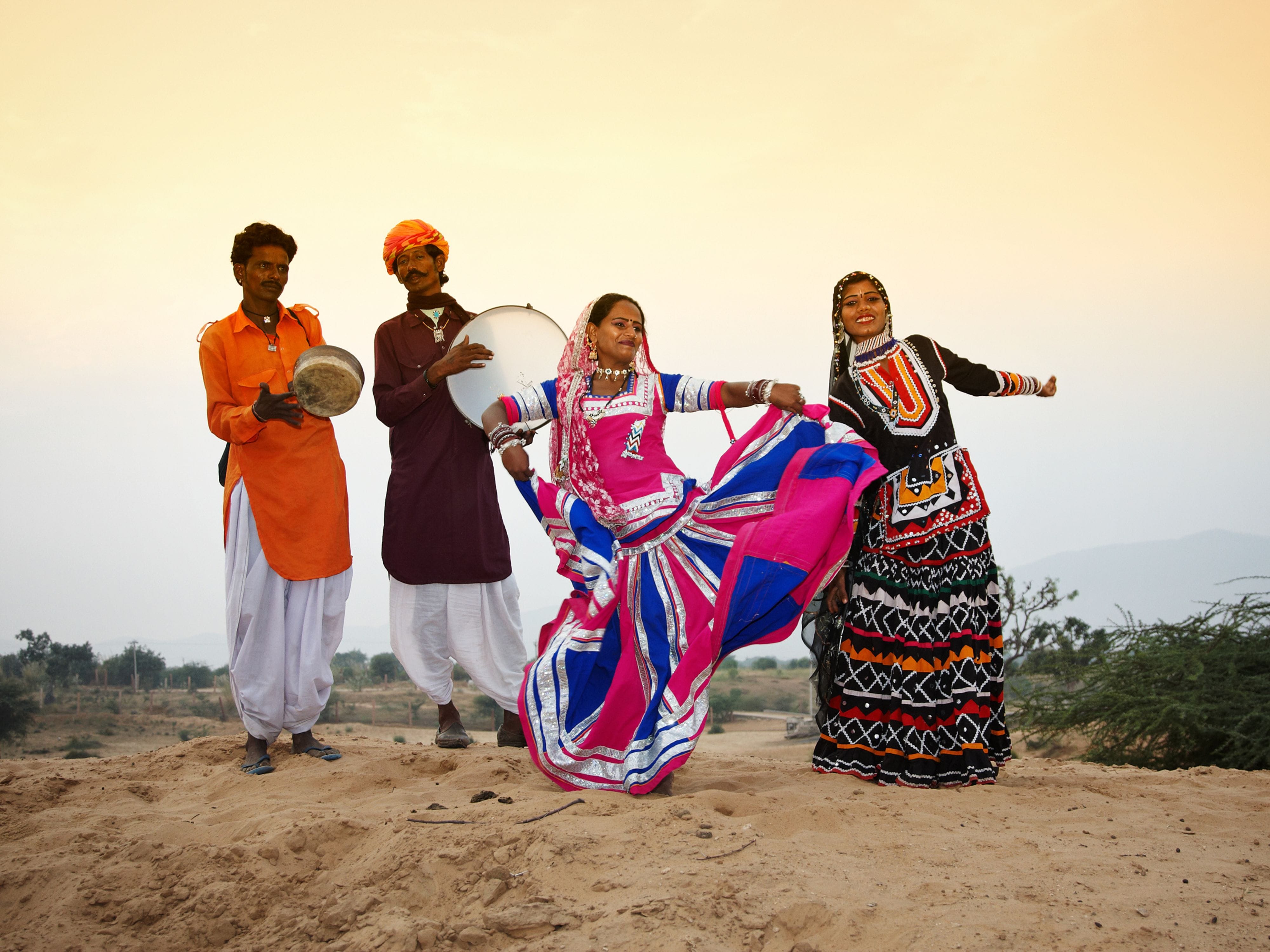 Two people playing the dafli as women perform Ghoomar