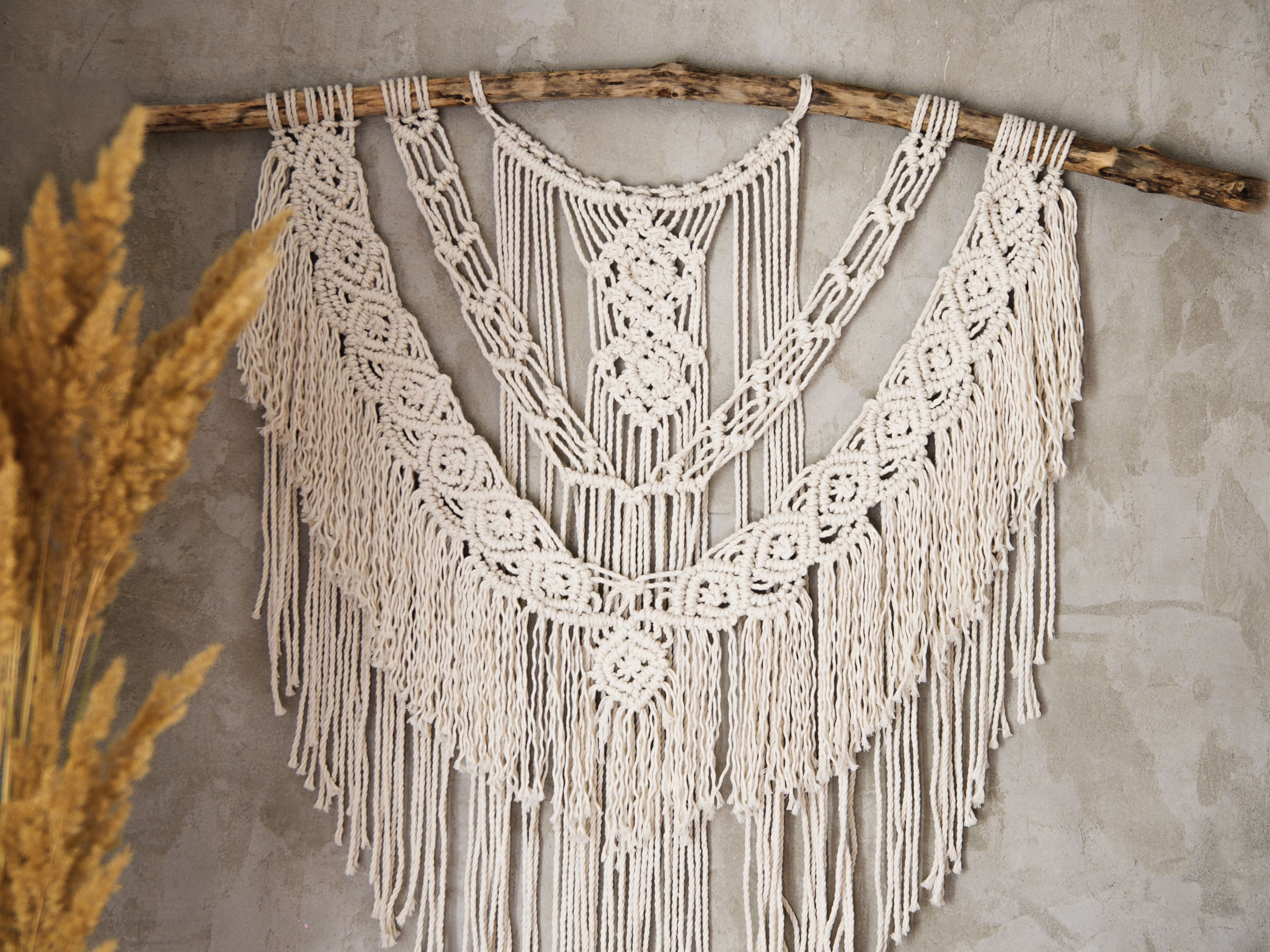 White cotton string wall hanging displayed on a wooden stick