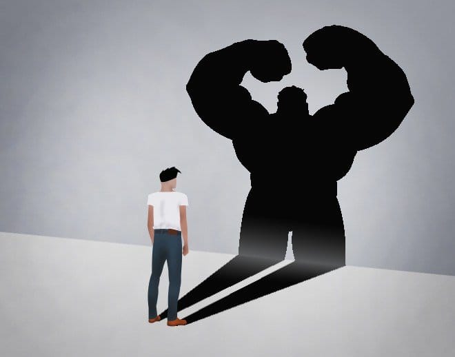 A man looks at his shadow, which is a muscular, powerful figure