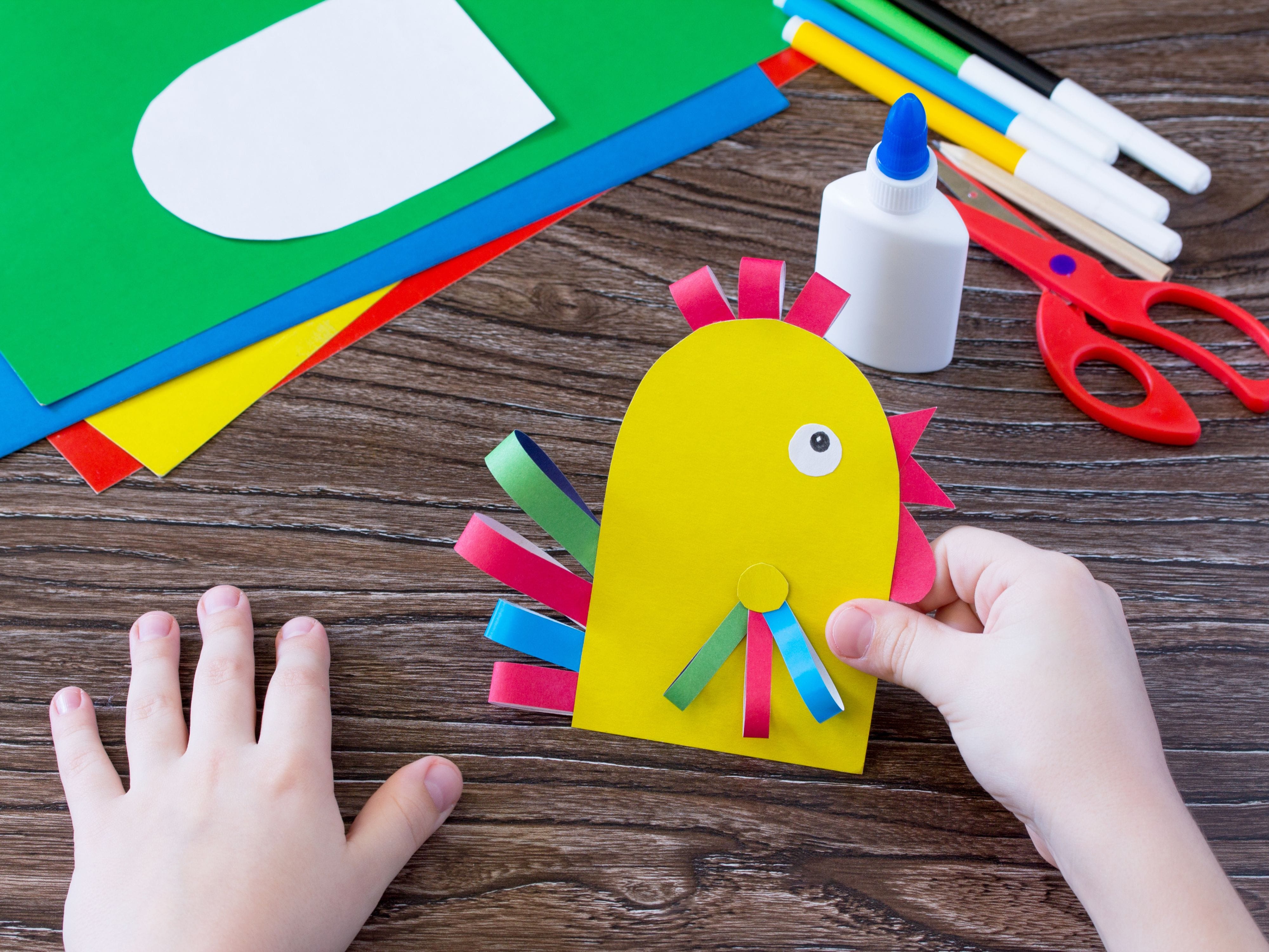Child's hands making paper chick craft