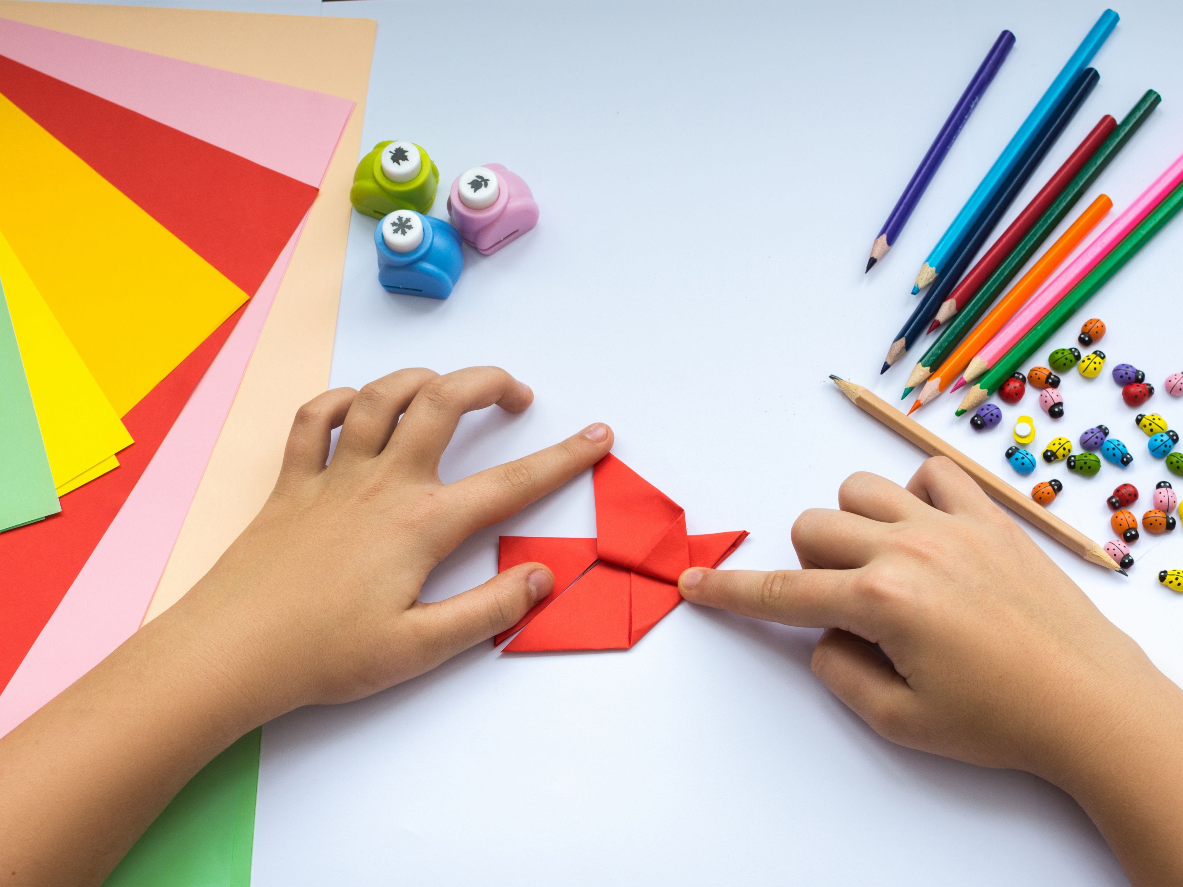 Hands folding red origami paper