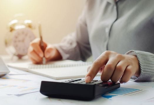 Person's hand on calculator, writing notes