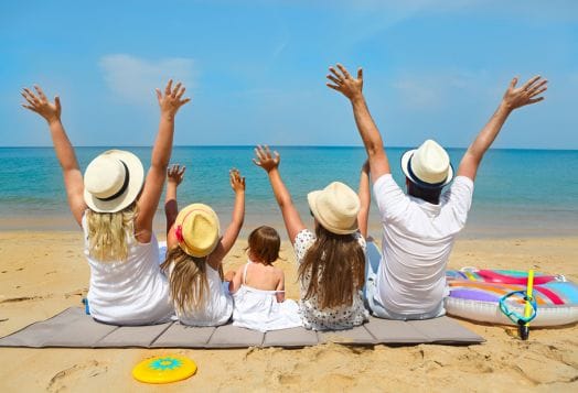 Family enjoying beach vacation with arms raised