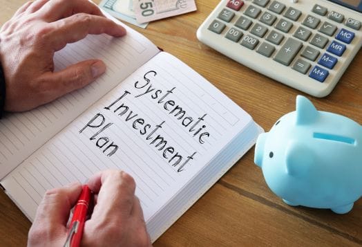 Hands writing "Systematic Investment Plan"