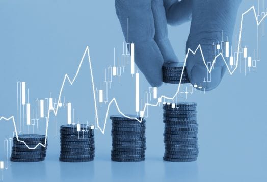 Hand stacking coins with rising graph