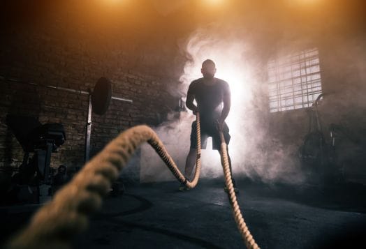 Man using battle ropes in a smoky gym