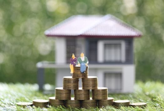 Couple on coin stacks in front of a house