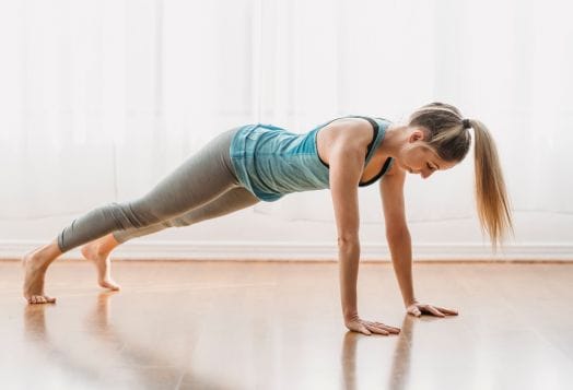 Woman performing a plank on a wooden floor