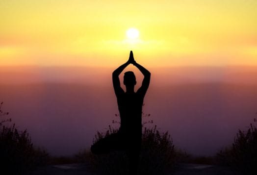 Silhouette of a person meditating at sunset