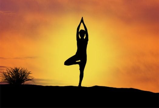 Silhouette of a person in tree pose at sunset