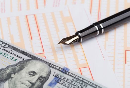 A hundred dollar bill and a fountain pen on deposit slips