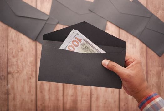 Hand holding an envelope with hundred dollar bills