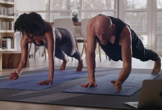 Two people doing forearm planks on yoga mats