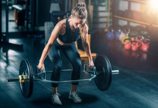 Woman preparing for a trap bar deadlift at a gym