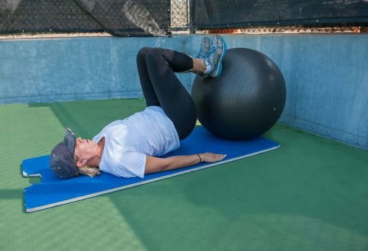 Woman doing glute bridges with a fitness ball
