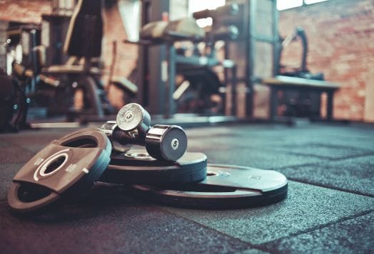 Weight plates and dumbbells on a gym floor