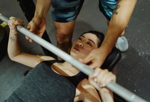 Woman getting a spot during a bench press at a gym