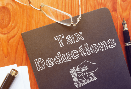 A notebook with "Tax Deductions" written on it, along with glasses and a pen