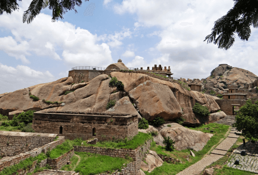 An ancient fort complex built on a rocky hill under a cloudy sky