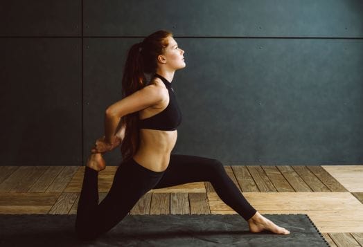 A woman with long red hair doing a yoga pose on a mat