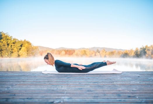Woman doing yoga by a misty lake