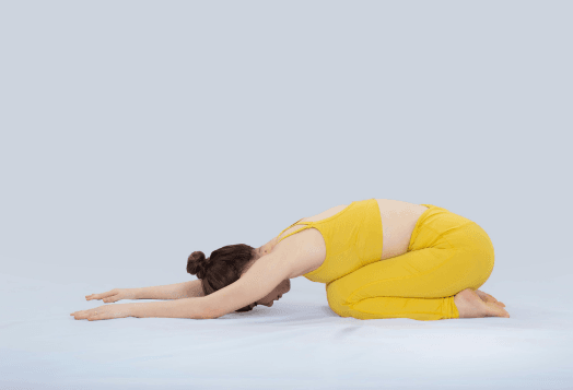 Woman in yellow, child's pose on white