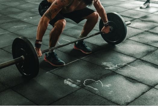 Weightlifter gripping barbell on gym floor