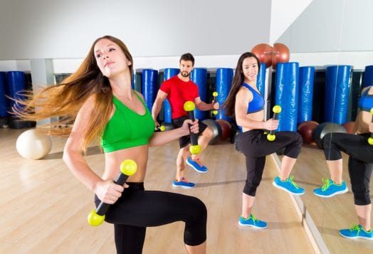 People exercising with weights in a gym with mirrors and equipment