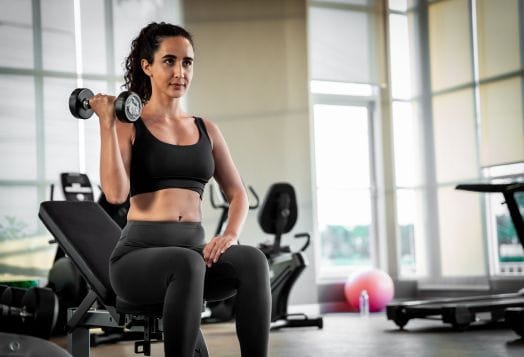 Woman in black gym attire doing bicep curls with a dumbbell