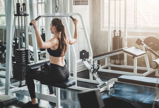 Woman doing lat pulldowns on a machine in a bright gym