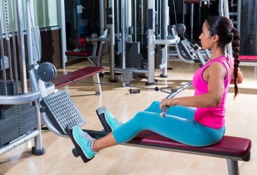 Woman in pink and blue exercising on a seated row machine
