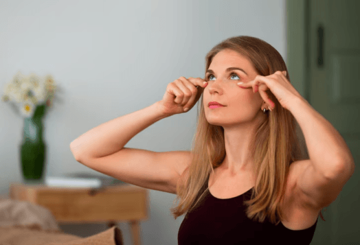 A woman pinches the skin around her eyes, looking up