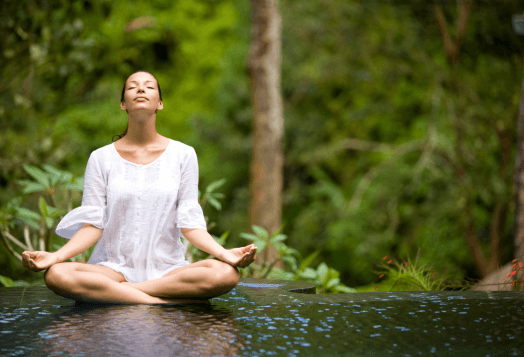 Serene woman meditating outdoors in a tranquil natural setting
