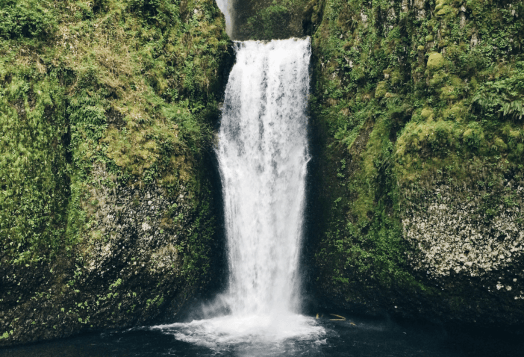 The Netravali Waterfalls (Savari/Mainapi), a powerful cascade of water plunging into a pool surrounded by dense green vegetation