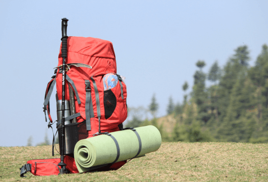 Red trekking backpack with a sleeping mat and pole