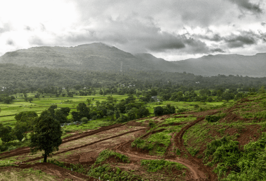 Lush green valley with mountains and farmland under a cloudy sky