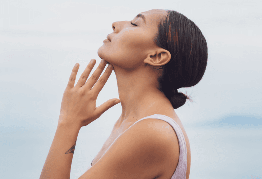 Woman performing Chin Tucks exercise, gently touching her neck
