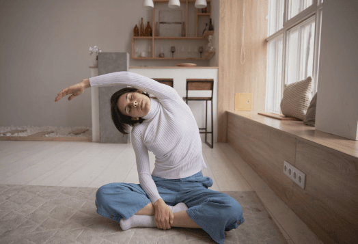 Woman performing an Ear-to-Shoulder Assisted Stretch, sitting cross-legged