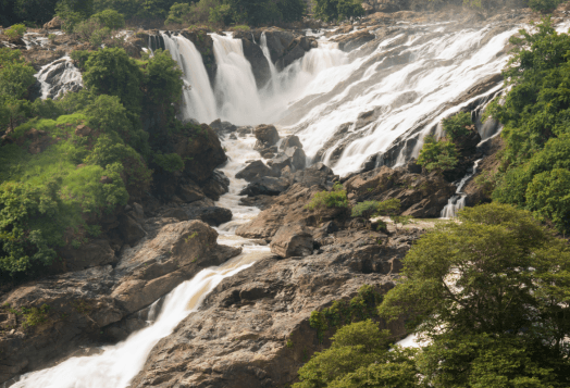 The impressive Shivanasamudra Falls, a wide and powerful waterfall with multiple cascades flowing over rocky terrain, showcasing both Gaganachukki and Bharachukki