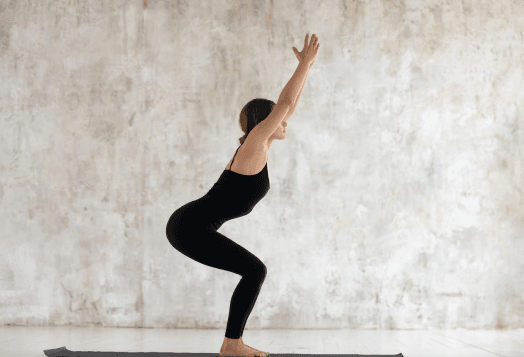 A woman in a black outfit in Chair Pose (Utkatasana)
